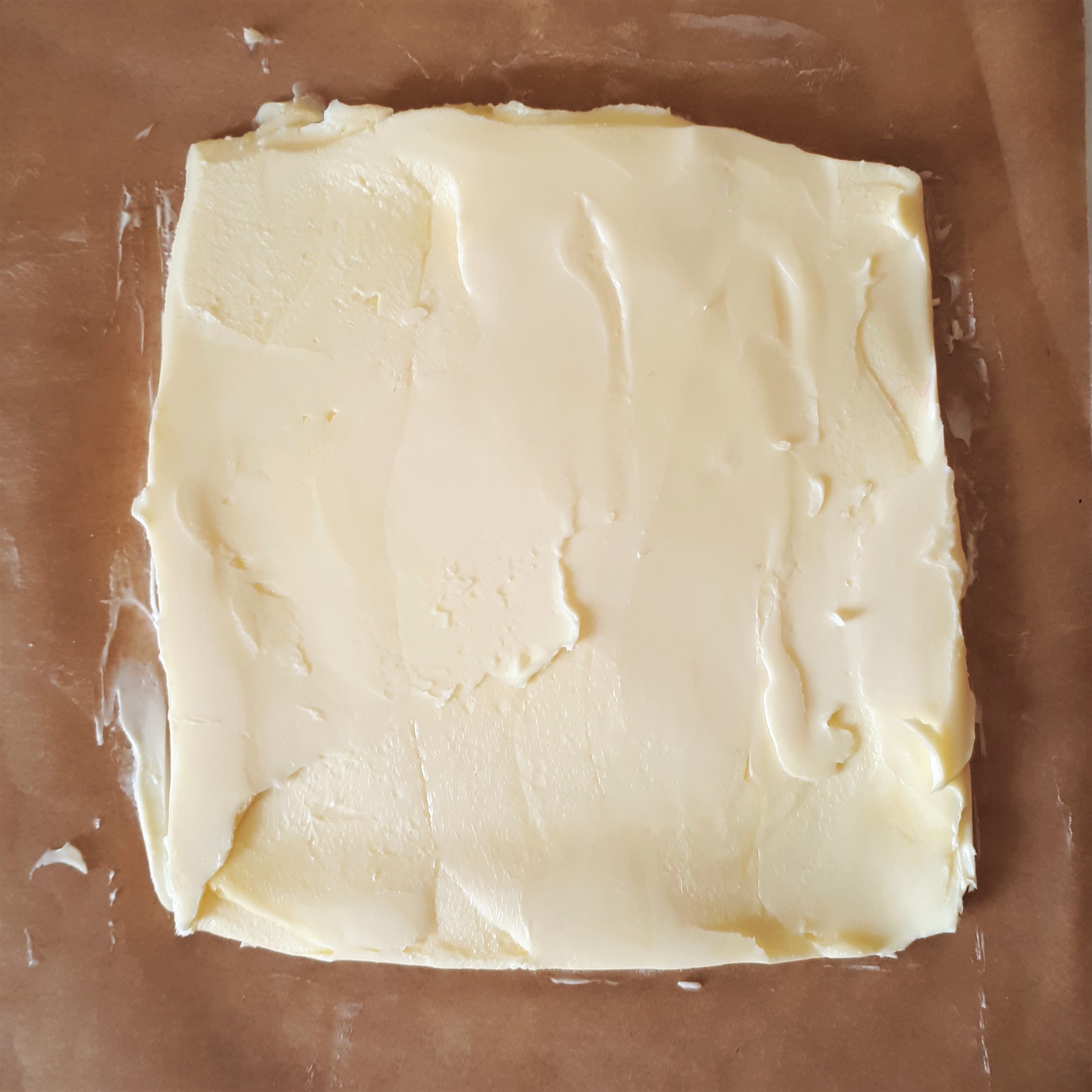 Maslo na papieri na pečenie rozvaľkané na štvorec