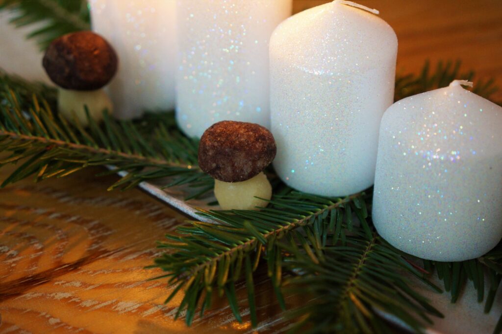 Štyri adventné sviečky na bielej obdĺžnikovejtácke vetvičy ihličia marcipánové hríbiky