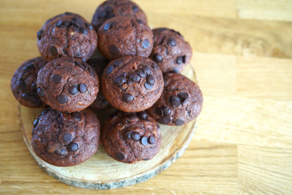 Tmavé kakové muffiny s kúskami čokolády na drevenom podnose na drevenej chuynskej linke